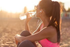 woman drinking water after exercising