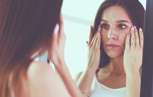 woman checking her skin in the mirror