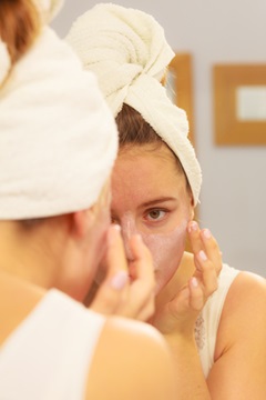 woman putting skin moisturizer on her face