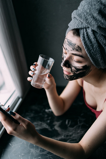 woman relaxing with an activated charcoal facemask on her face