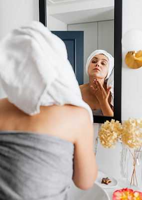 woman looking at her skin in the mirror