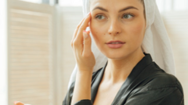 young woman putting moisturizer on her face to prevent wrinkles