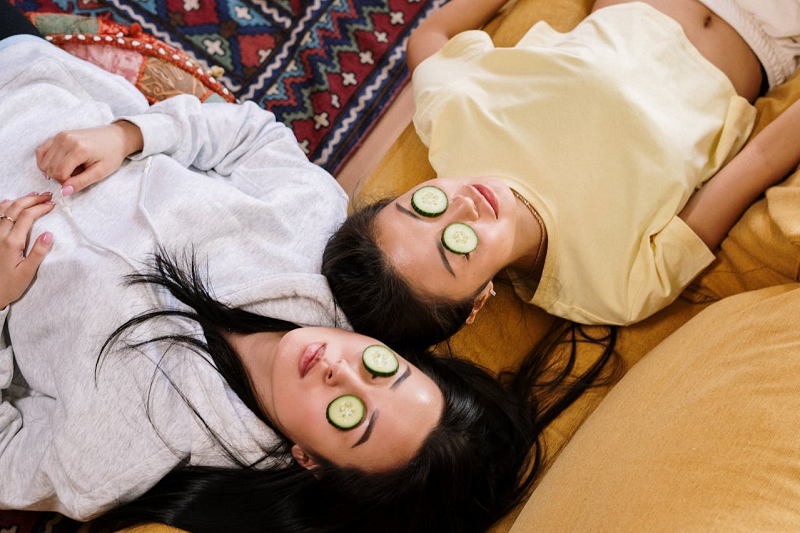 two women with cucumber slices on their eyes