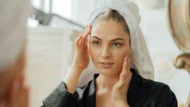woman looking at her face in the mirror